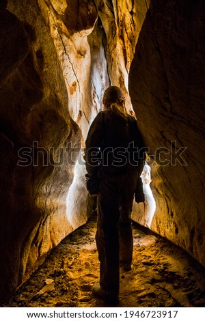 Speleologist exploring a deep cave discovering new underground passage