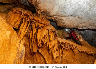 A speleologist with helmet and headlamp exploring a cave with rich stalactite and stalagmite formations. High quality photography. - Powered by Shutterstock