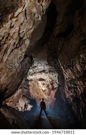 Spelunkers exploring a deep cave discovering new undexplored passage. Speleology is a science and extreme sport dedicated to the study of the underground 