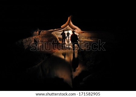 Spelunkers exploring a mystic cave river 