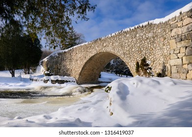 Spencer Creek Flowing Under A Stone Bridge At Webster Falls Conservation Area Park In Winter