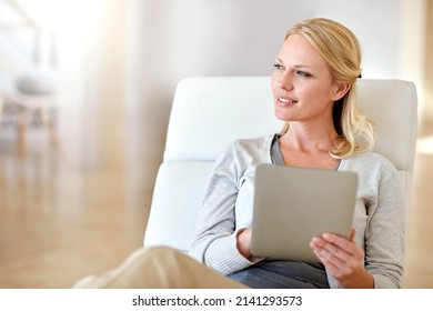 Spending a free day catching up online. Shot of a woman using a digital tablet in the living room.