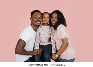 Spending Time With Family Is Fun. Close Up Portrait Of Excited African American Man, Woman And Girl Laughing And Posing Isolated On Pink Studio Wall. Cheerful Father Hugging Daughter And Wife.