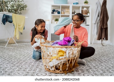 Spending Time Together While Doing Household Chores, Mom Playing With Laughing Daughter While Sorting Colorful Laundry, Taking Out A Girl's T-shirt From The Basket While Making Fun Of Her