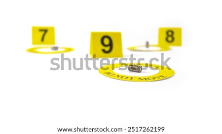 A spent bullet casing placed within a yellow circle, labeled with the text Evidence, Do Not Move, with a blurred number 9, 8 and 7 tag, set against a white background, concept of crime investigation.