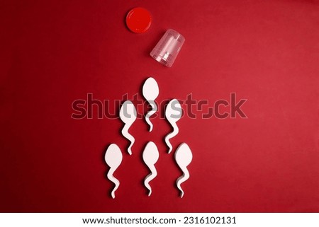 Spermatozoa and sperm sample plastic container on red background. Semen analysis, male fertility test, sperm  bank and donation concept. 