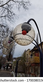 Sphere Shape Transparent Glass Lampshade Of Vintage Style Streetlight Closeup On Grey Sky Background. Raindrops At Glass Surface Of Lamp With Red Light Bulb Inside. Rainy Day Cityscape.