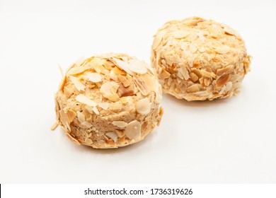 Spherical airy cake based on meringues and nuts, decorated with almond petals, close-up on a white background