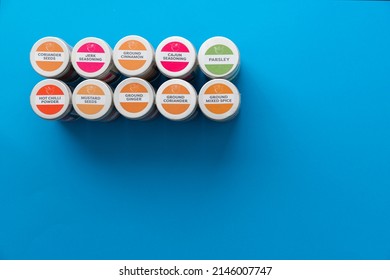 Spice Containers Or Jars Lined Up On A Blue Colour Textured Background With Negative Space For Text