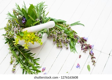 spice and herbal plants in a mortar, white wooden table background