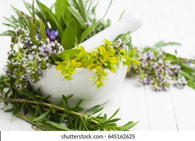 spice and herbal plants in a mortar, white wooden table background
