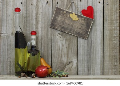 Spice oil decanters by pears with blank wood sign with hearts hanging on wooden background