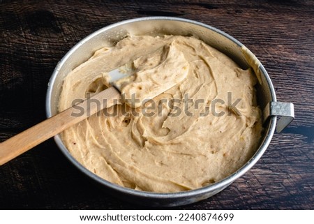 Spiced Cake Batter in a Round Cake Pan with a Spatula: Thick cake batter spread in a circular metal cake pan with a silicone spatula