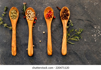 Spices And Herbs In Olivewood Spoons On A Rustic Stone Counter Background. Close Up Looking Down. Copy Space.