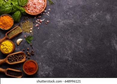 Spices and herbs over black stone background. Top view with free space for menu or recipes.