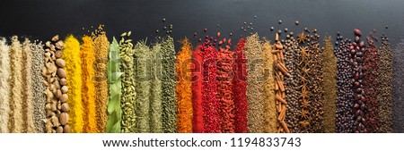 Spices and herbs for website headers. Seasoning scattered on black table, background for packing with food.