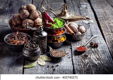 Spices, pepper grinder, spoon with seeds at grey wooden background 
