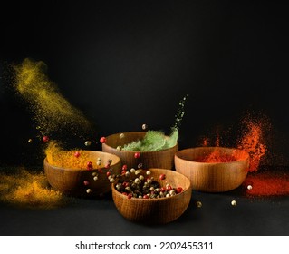 Spices and seasonings powder splash, explosion. Set of colorful spices in wooden bowls, isolated on black background. Freeze motion photo