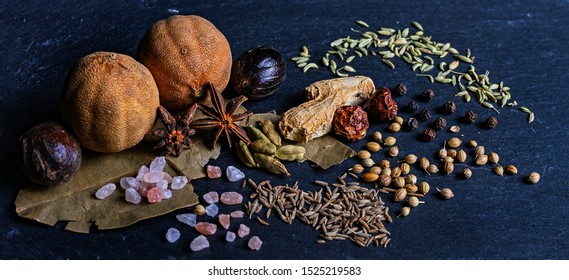 Spices set on the black rock board. Bell pepper seeds dried, nutmeg, anise, alpine salt, bay leaf, ginger. Macro view selective focus..