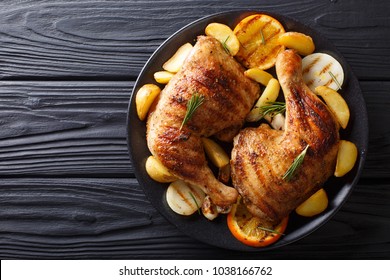 Spicy Bbq Chicken Legs With Grilled Oranges, Onions, Garlic And Potatoes Close-up On A Plate On A Table. Horizontal Top View From Above
