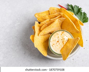 Spicy cheese sauce (dip) with nachos (tortilla chips) ready to eat. Mexican snack or appetizer. Traditional fast food. Top view, concrete background. Copy space. - Powered by Shutterstock