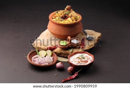  Spicy chicken biryani in traditional handi or clay pot. served with onion raita
