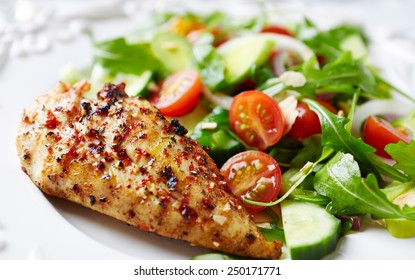 Spicy chicken breast with cherry tomatoes, cucumber, white onion, leek and fresh rocket. Home made tasty food. Concept for a healthy and hearty meal. Close up. Paleo diet recipe