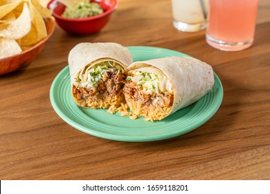 Spicy chicken burrito in a flour tortilla. Authentic Mexican food served in a restaurant with chips and salsa.