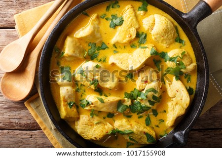 Spicy chicken in a sauce of coconut milk close-up in a frying pan. horizontal top view from above
