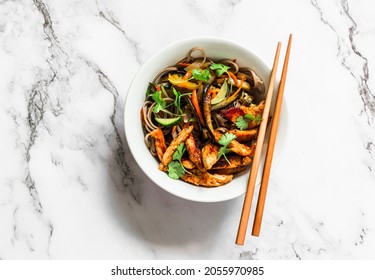 Spicy chicken, stir fry seasonal autumn vegetables with soba noodles on a light background, top view          