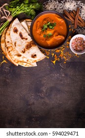 Spicy chicken tikka masala in bowl on rustic wooden background. With rice, indian naan butter bread, spices, herbs. Space for text. Traditional Indian/British dish. Top view. Indian food. Copy space