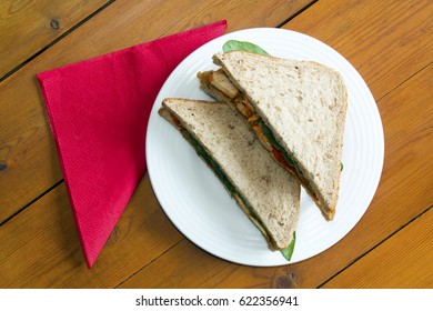 Spicy Chicken Tikka Sandwich On A Table With A Napkin From An Overhead Perspective