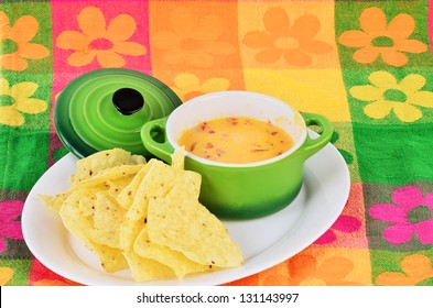 Spicy Chili Con Queso Dip In Bright Green Bowl With Tortilla Chips Sitting On Colorful Place Mat.