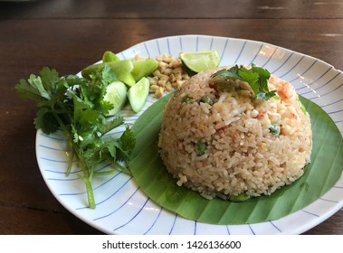 Spicy Chili paste fried rice with fresh shrimp and smelly bean Thai style serving with fresh vegetable on Banaba leaves and white plates