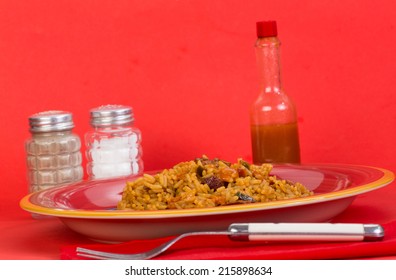 Spicy Creole Sausage Jambalaya In Bright Red Setting With Louisiana Hot Sauce