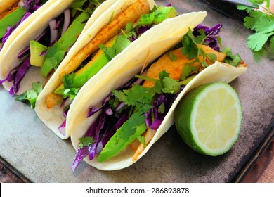 Spicy Fish Tacos With Red Cabbage Slaw, Avocado And Lime Juice On Vintage Tray