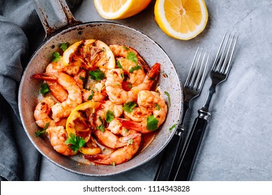 Spicy garlic chilli Prawns Shrimps on frying pan with lemon and cilantro