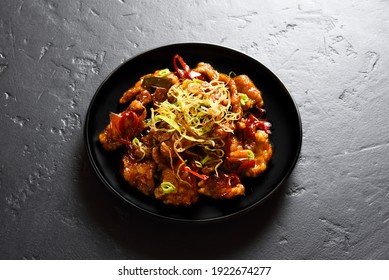 Spicy garlic fried chicken (Kkanpunggi). Asian chicken in sweet and sour sauce on plate over black stone background. Close up view