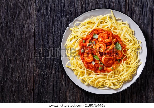 Spicy Garlic Shrimp\
Pasta With Tomato Sauce, prawns in tomato sauce with noodles,\
Shrimp alla Marinara on plate on wooden table, horizontal view from\
above, flat lay, free\
space