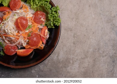 Spicy Glass Noodle Salad With Salted Egg Yolk In A Black Plate