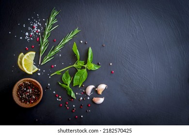 spicy green herbs as ingredients for cooking, consisting of red, black, white, pepper seeds, rosemary, basil, lime, and salt on a slate table. food background dark tone top view with copy space - Powered by Shutterstock