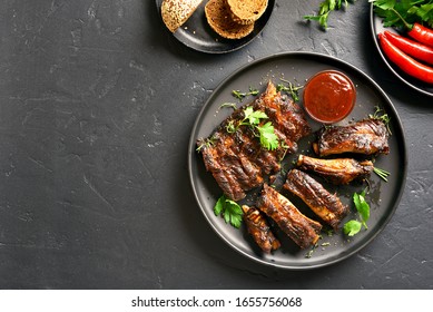 Spicy Grilled Spare Ribs On Plate Over Black Stone Background With Free Text Space. Tasty Bbq Meat. Top View, Flat Lay