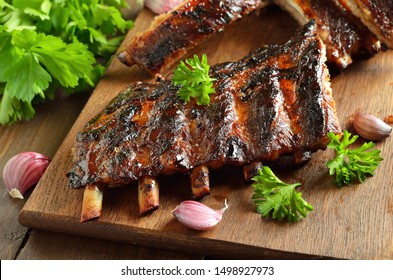 Spicy hot grilled spare ribs on cutting board, close up