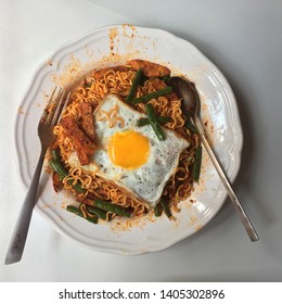 Spicy Instant Fried Noodle With Sunny Side Up Fried Egg On White Plate