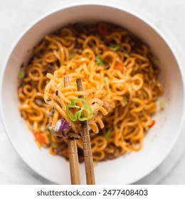 Spicy instant noodles with slices of green and red chili, spicy ramen noodles with chopsticks in a white ceramic bowl - Powered by Shutterstock