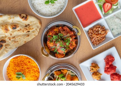 Spicy Jaipuri with assorted Indian dishes Rice, Naan Bread, Sauces, Pakora on brown wooden table - Powered by Shutterstock