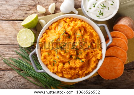 Spicy mashed sweet potato with onion, garlic and lime close-up in a saucepan on a table. horizontal top view from above

