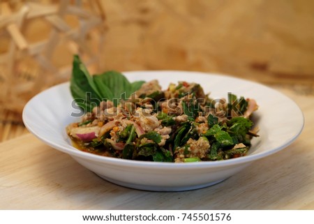 Spicy minced pork salad, famous spice street food of Thailand served on white plate with some vegetable and sticky rice,  easy and delicious food for local and foreigner especially for weight control 