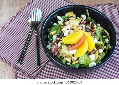 Spicy nutty fruity quinoa salad in black ceramic bowl., Homemade quinoa with spinach and fruit salad - Powered by Shutterstock