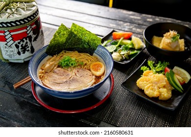 Spicy pork tonkotsu chashu ramen combo with ebi mayo, agedashi tofu in the traditional Japanese ramen restaurant, with Japanese fonts sake barrel translation: Invincible Great Gate